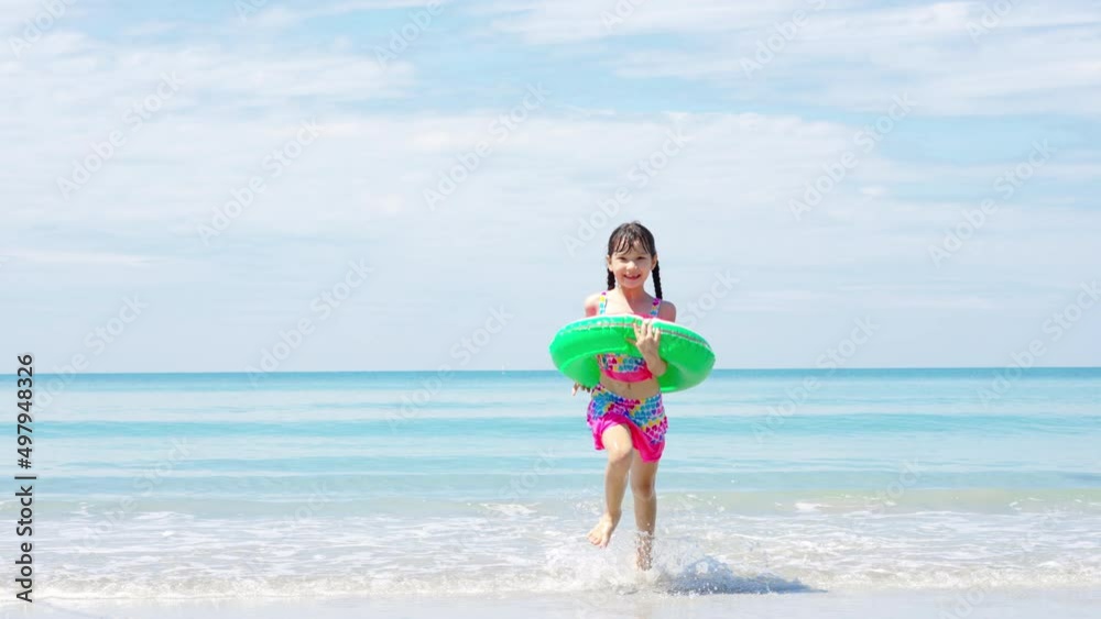 Portrait of Smiling Asian child girl in swimwear running and playing on tropical beach in summer sunny day. Happy little girl enjoy and fun outdoor activity lifestyle on travel vacation at the sea Portrait of Smiling Asian child girl in swimwear running and playing on tropical beach in summer sunny day. Happy little girl enjoy and fun outdoor activity lifestyle on travel vacation at the sea