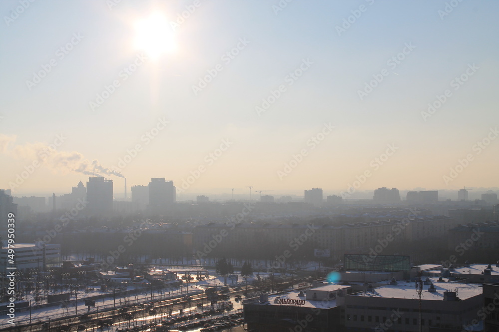 A residential area with typical Soviet arhitecture in the foreground on a sunny foggy day