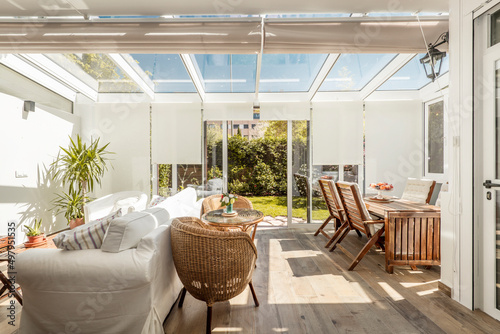 Terrace with access to the garden with white aluminum carpentry and glass with large sliding doors with light wooden floors and wicker furniture and a large white sofa