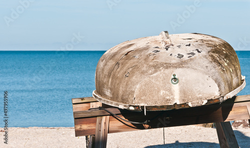 front view, medium distance of a fiberglass boat hull, deteriorating on wood sawhorses on a tropical island photo