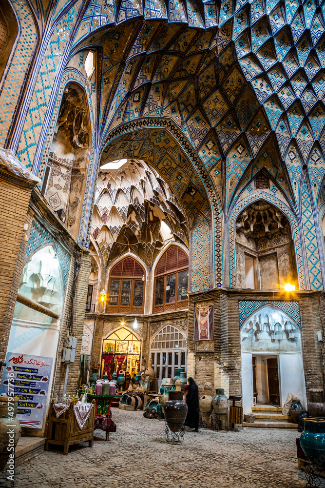Woman with chador walking through inner square in the old bazaar of Kashan, Iran