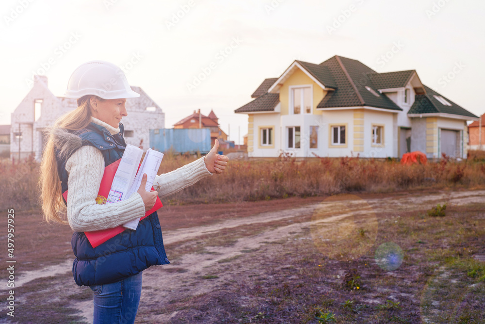 Young female construction specialist reviewing blueprints at construction site