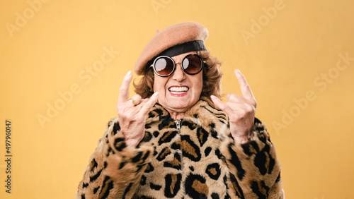 Foto Stylish senior woman showing rock n roll gesture while posing on isolated background