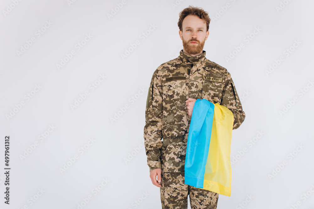 Ukrainian patriot soldier in military uniform holding a yellow and blue flag on a white background Ukrainian patriot soldier in military uniform holding a yellow and blue flag on a white background