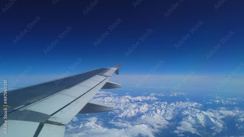 Airplane flight. Wing of an airplane flying above the snow mountain. View from the window of the plane. Aircraft. Traveling by air. 4K UHD video Airplane flight. Wing of an airplane flying above the snow mountain. View from the window of the plane. Aircraft. Traveling by air. 4K UHD video