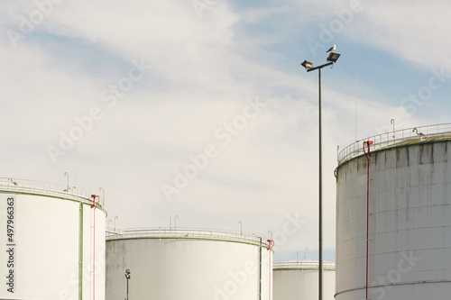 Close-up of white fuel tanks in a sunny day with sky and clouds above