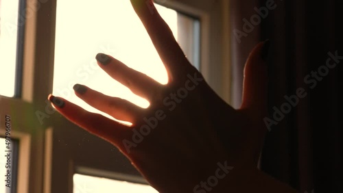 Waving hand to glare of sun flare in afternoon time, urban street. Woman's hand on balcony, sunbeams an gesture.