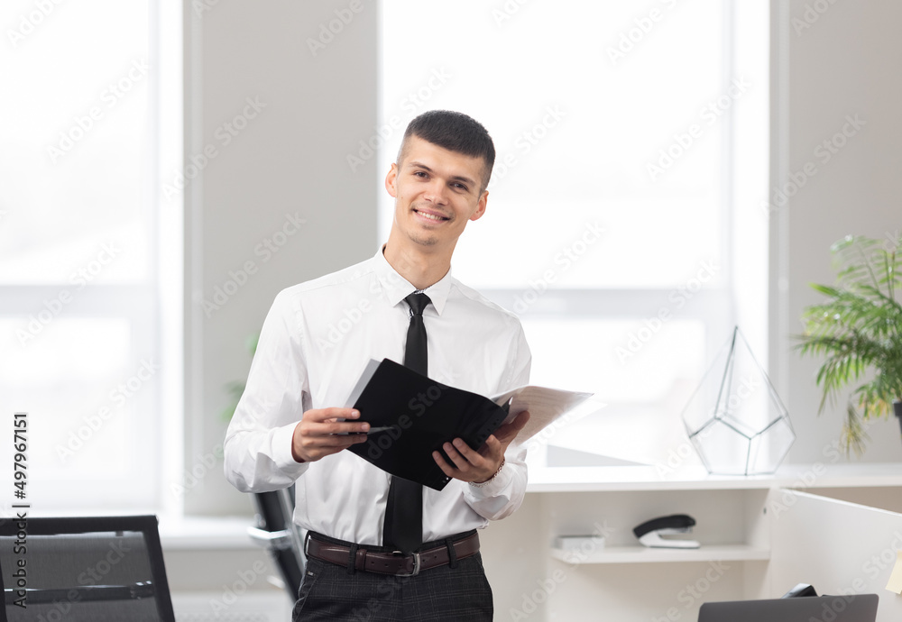 young attractive man in a bright office holding a folder young attractive man in a bright office holding a folder