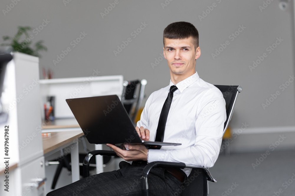 Successful happy business man sitting at a desk in the office, and uses a laptop. Successful happy business man sitting at a desk in the office, and uses a laptop.