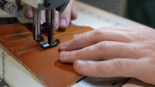 A woman sews leather on a sewing machine and makes leather embroidery. Seams and threads