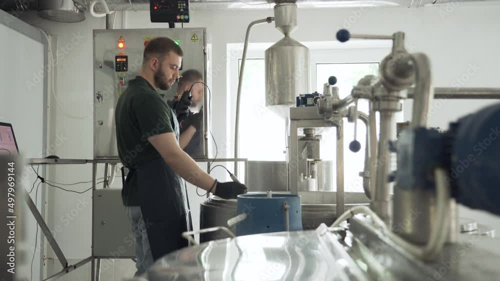 A young cheesemaker controls the temperature of the cheese mixture. Cheese production technology. Production premises. A young cheesemaker controls the temperature of the cheese mixture. Cheese production technology. Production premises.