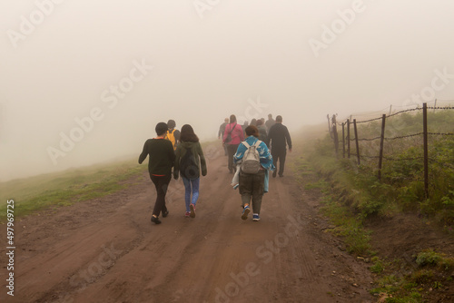 Canvas Print Back view of refugees walk to the border in a cold day under fog