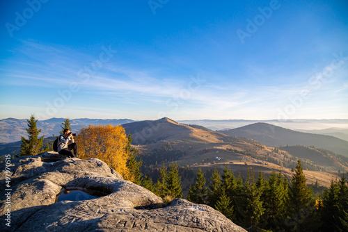 Traveler on the top of the mountain photographs the mountain landscape