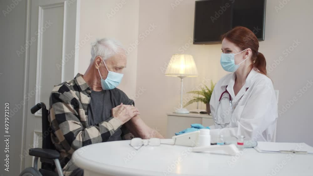 The doctor makes a vaccination to a pensioner and shows the thumb The doctor makes a vaccination to a pensioner and shows the thumb
