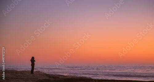 solitary woman in twilight at the seashore contemplates the ocean