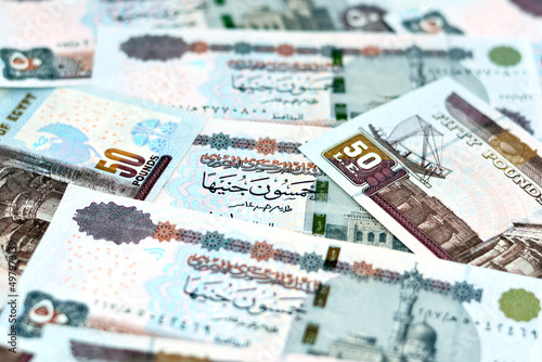 A pile of Egyptian money banknotes of 50 LE fifty pounds features Abu Hurayba Mosque on obverse side and n image of temple of Edfu, winged scarab and a pharaonic boat on the reverse, selective focus photo