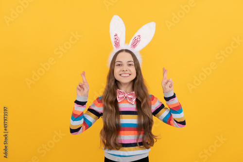 happy easter kid in bunny ears and bow tie on yellow background. make a wish