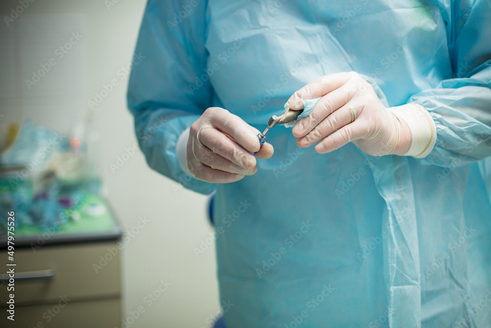 Professional dentist holding stomatological tool in hospital during surgery
