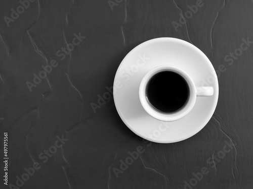 White cup of black coffee and saucer on the table, top view