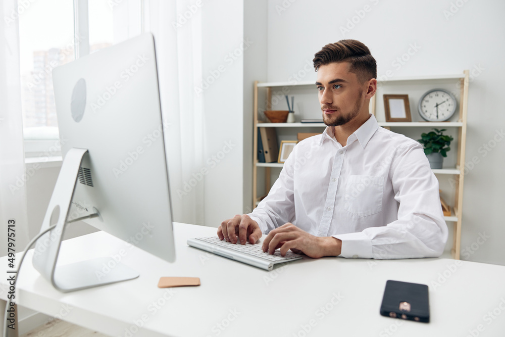handsome businessman sitting at a desk in front of a computer with a keyboard workplace