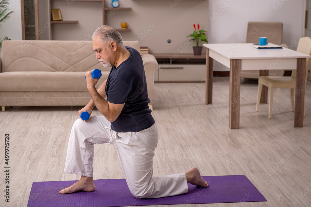 Old man doing sport exercises at home