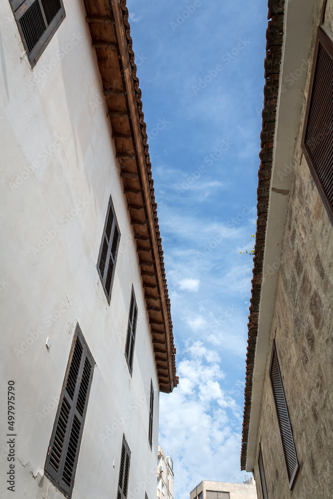 Blue sky with white clouds between two old houses