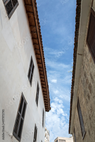 Blue sky with white clouds between two old houses