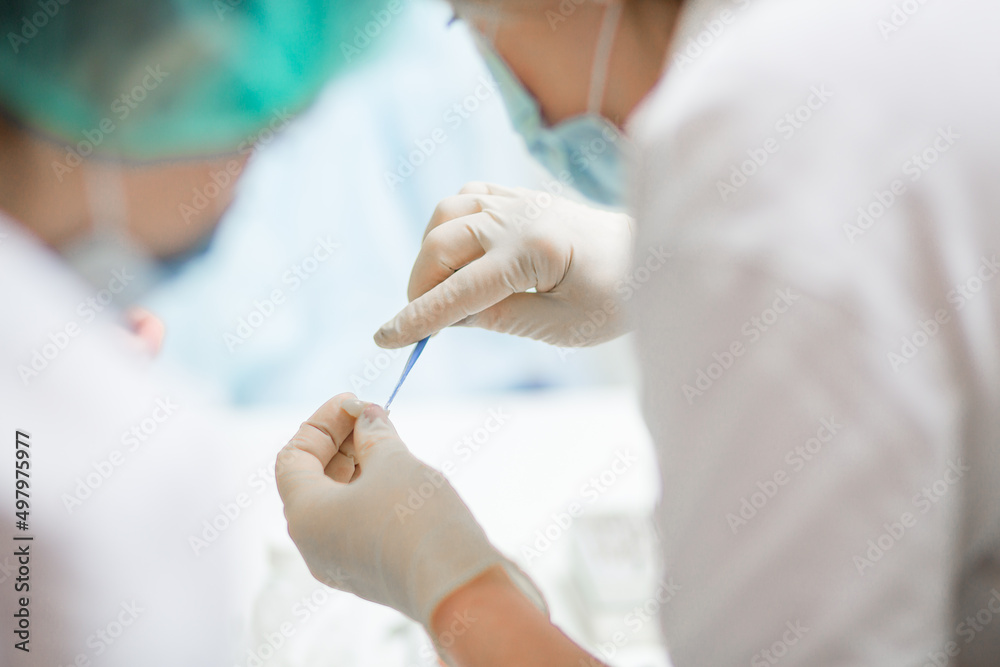 Professional dentist holding stomatological tool in hospital during surgery Professional dentist holding stomatological tool in hospital during surgery
