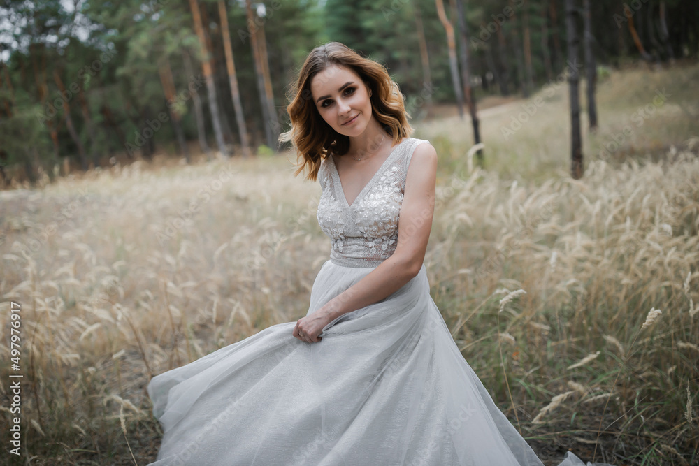 A beautiful, satisfied bride in a pine forest poses.