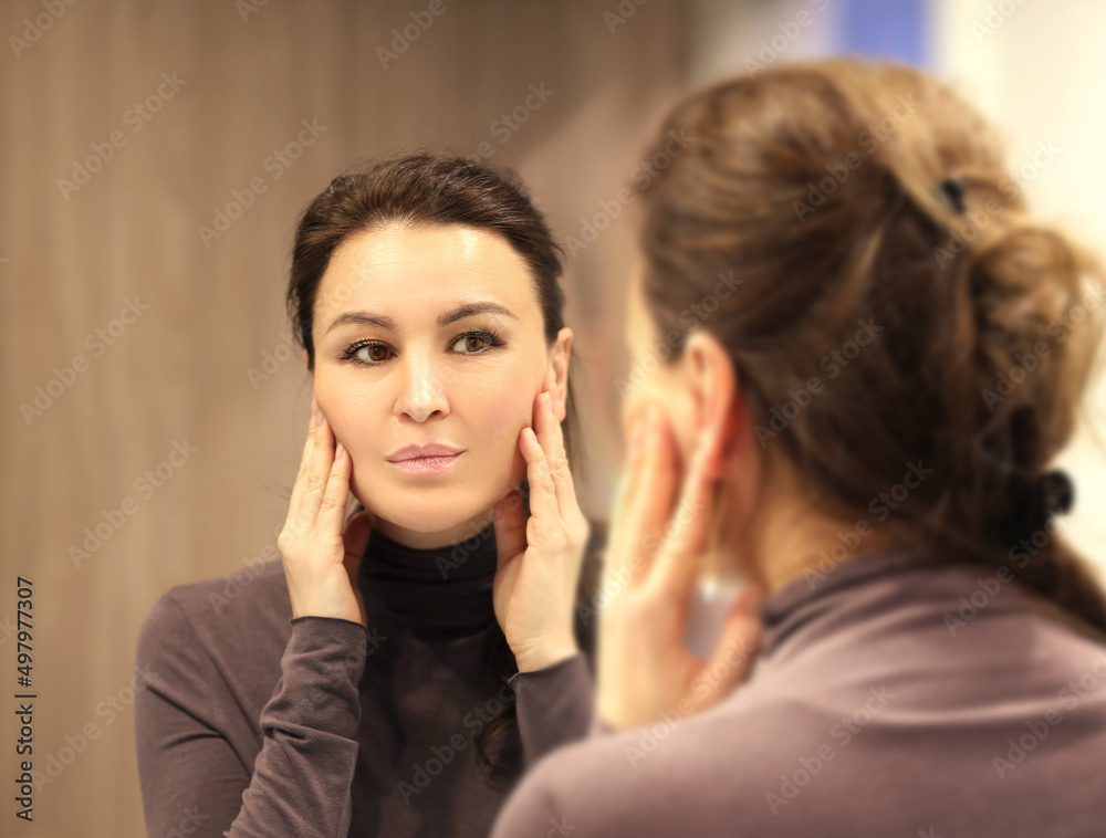 Woman looking in the mirror Applying the cream..Magic anti-aging cream. Woman looking in the mirror Applying the cream..Magic anti-aging cream.