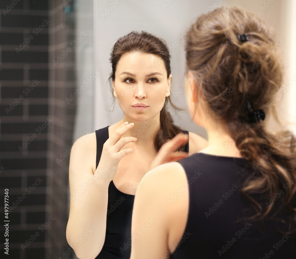 Woman looking in the mirror Applying the cream..Magic anti-aging cream.