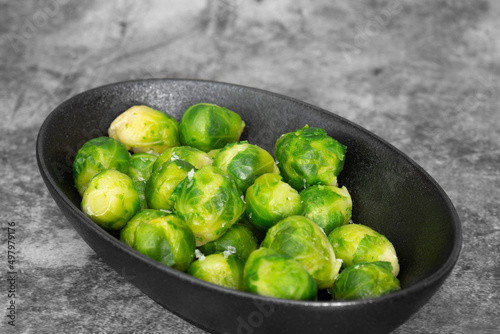 Brussels sprouts seasoned with sea salt in a black dish. On a stone background
