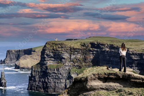 A women admires the Cliffs of Moher views, sea cliffs located at the southwestern edge of the Burren region in County Clare, Ireland