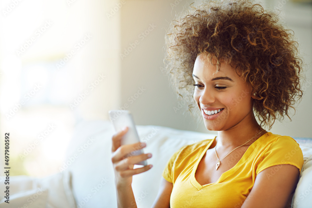 The message that brightened her day. Shot of a young woman using her phone on a relaxing day at home. The message that brightened her day. Shot of a young woman using her phone on a relaxing day at home.