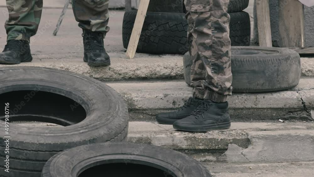 close-up. military feet shod in heavy army boots. old car tires. defensive post in wartime. gloomy day, autumn, summer. soldiers in camouflage military uniforms. in Ukraine. war activities.