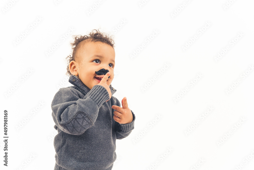 Funny happy hipster biracial kid touching his fake black mustache props over white background. High quality photo Funny happy hipster biracial kid touching his fake black mustache props over white background. High quality photo