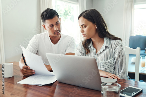 Its a numbers game. Cropped shot of a young couple using a laptop to their household budget in the living room at home.