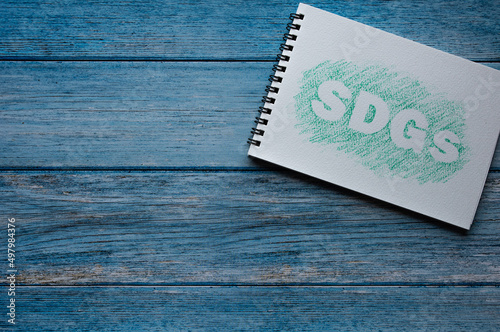 There is sketchbook with the word SDDs. It's placed on a wood board. photo