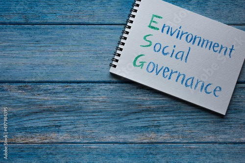 There is sketchbook with the word Environment, Social, Governance. It's placed on a wood board.