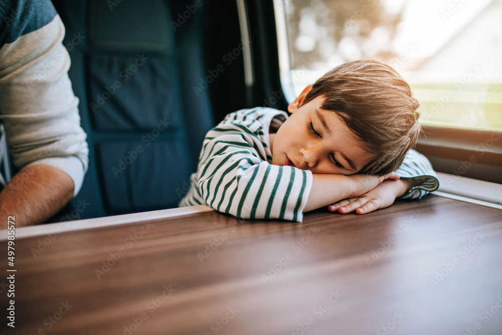 A cute little boy sleeps on a train next to his father. A cute little boy sleeps on a train next to his father.