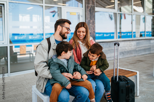 Happy ypung family with luggage in railroad station go together on vacation.