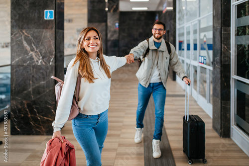 A happy couple at the train station is waiting for their train to arrive.