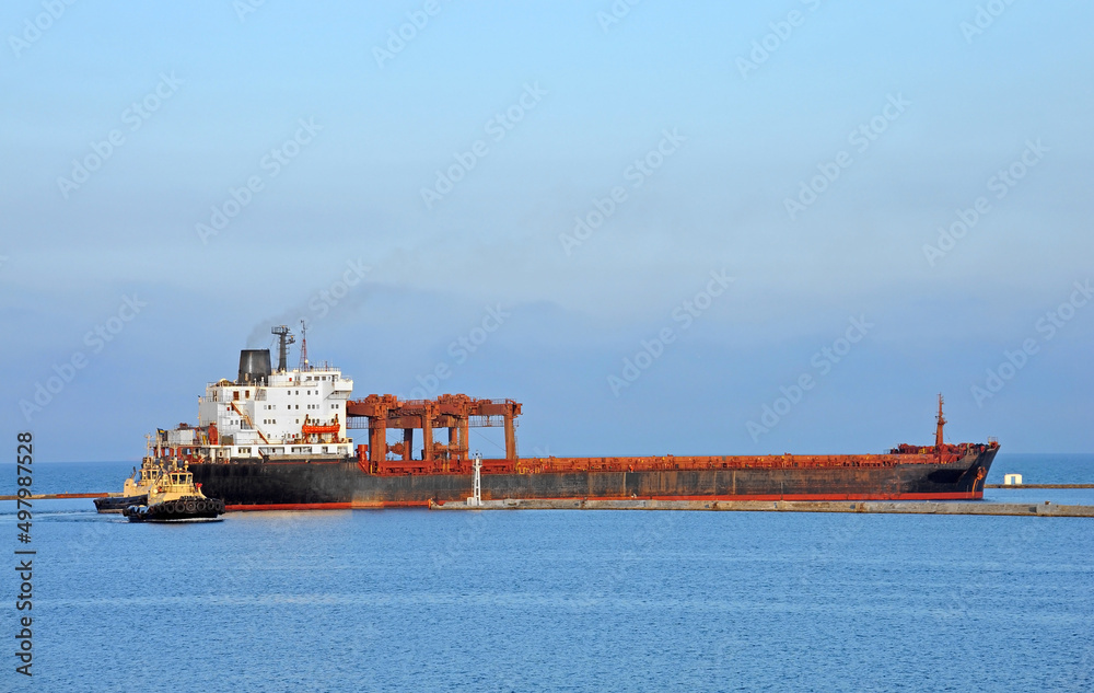 Fototapeta premium Tugboat assisting general cargo ship