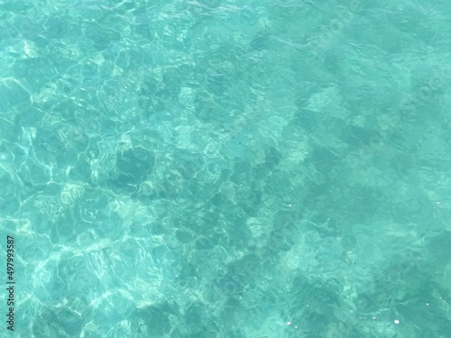 Beautiful crystal clear tropical water background with variegated aqua green color and abstract refracted sunlight