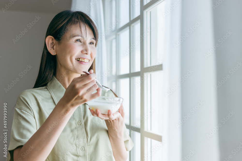 朝ヨーグルトを食べる中高年女性
朝ヨーグルトを食べる中高年女性