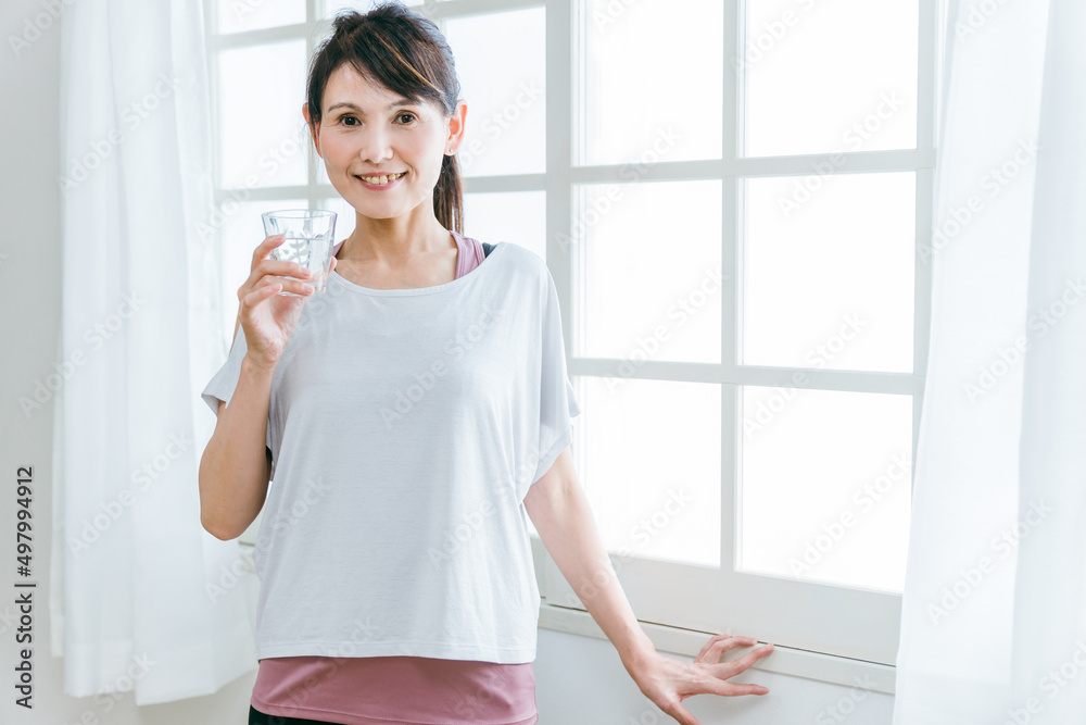 スポーツドリンク・水・白湯を飲むスポーツウェアの中高年女性