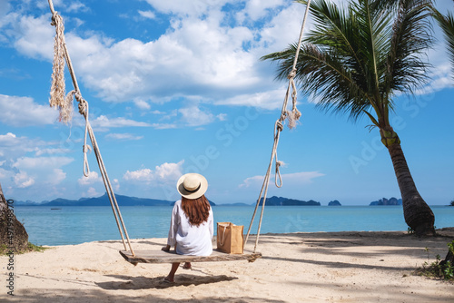 Rear view image of a young woman sitting on wooden swing by the sea © Farknot Architect