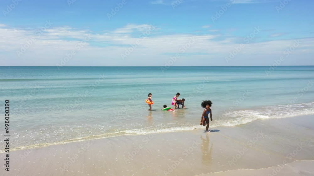 Group of Diversity little child boy and girl friends running and playing in sea water on tropical beach together on summer vacation. Happy children kid enjoy and fun outdoor lifestyle on beach holiday Group of Diversity little child boy and girl friends running and playing in sea water on tropical beach together on summer vacation. Happy children kid enjoy and fun outdoor lifestyle on beach holiday