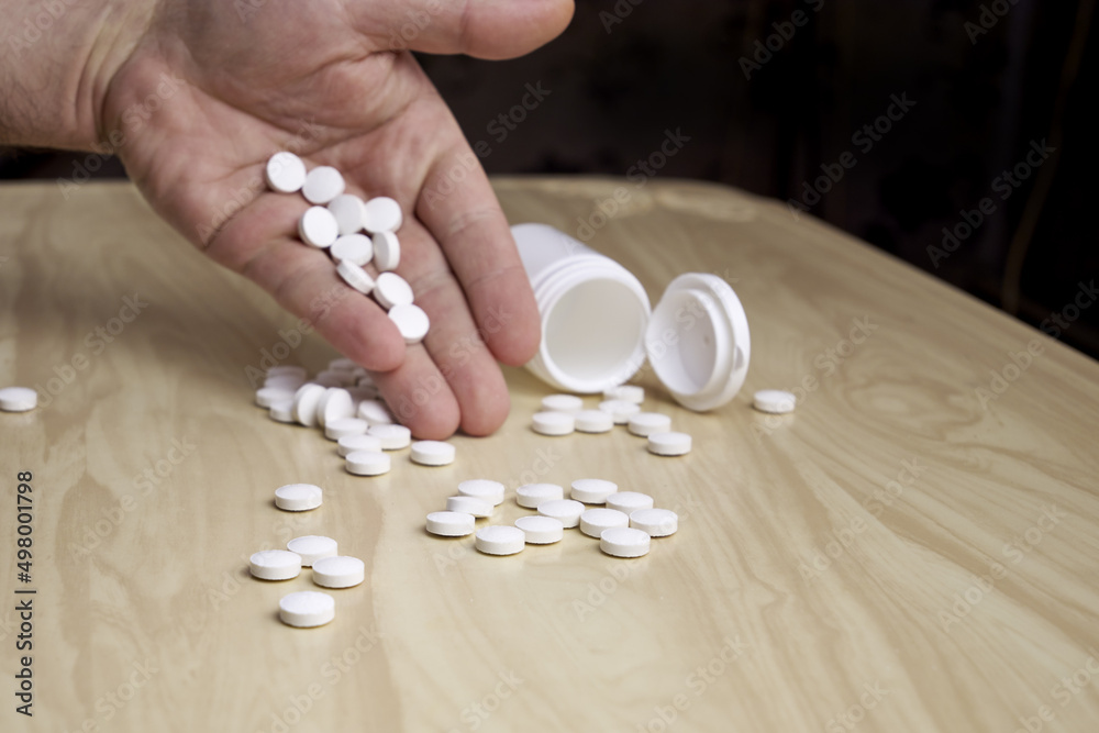 a man pours pills out of a plastic bottle on the table a man pours pills out of a plastic bottle on the table