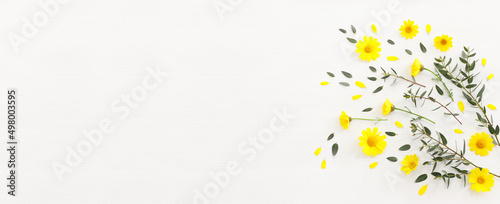 Top view image of yellow chrysanthemum field flowers composition over wooden white background. Flat lay